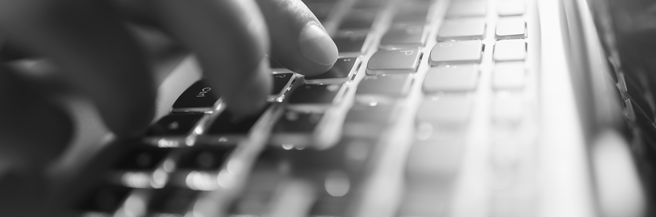 Close-up of a hand typing on a keyboard. Typing on a laptop keyboard to contact Load Controls for industrial power monitoring support 