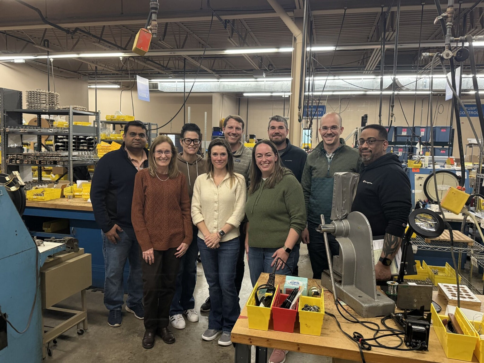 Load Controls team members posing together in the company manufacturing and production facility. Group of people posing for a photo in a workshop or factory setting. 